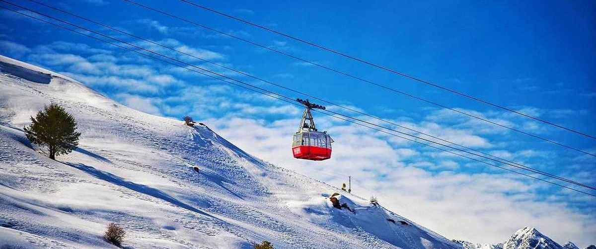 Auli Ropeway gliding over green hills with Himalayan views — best places to visit in summer in India for scenic rides and mountain adventure.