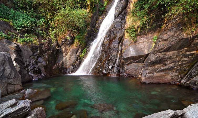 Bhagsunag Temple and Waterfall surrounded by rocky hills and greenery — best places to visit in summer in India for spiritual and natural retreat.