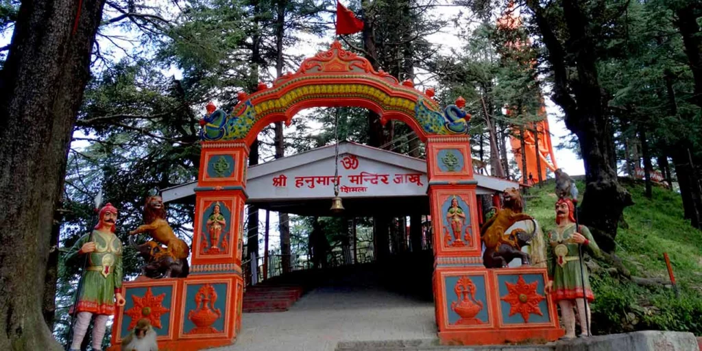 Entrance gate of Jakhoo Temple surrounded by pine trees — best places to visit in summer in India for peaceful Himalayan getaways.