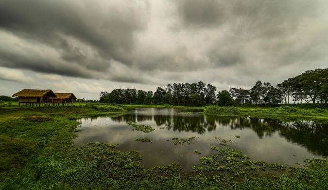 Scenic view of Majuli Island with a solo traveler cycling past lush greenery and traditional huts — one of the best places in India to travel solo.