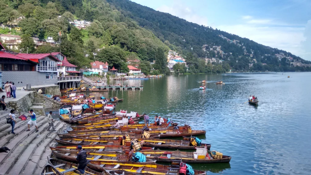 Boats floating on the calm waters of Naini Lake with forested hills in the background — best places to visit in summer in India for serene lake views.