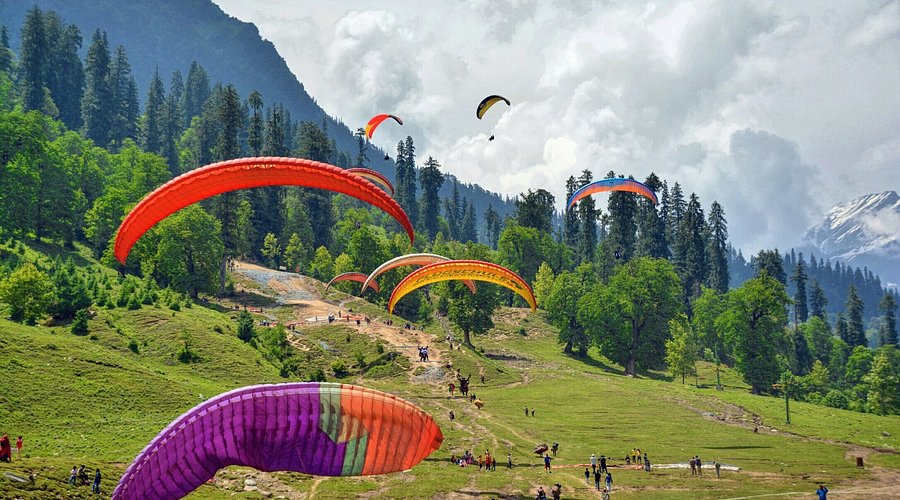 Solang Valley with green meadows, snow patches, and paragliders in the sky — best places to visit in summer in India for adventure lovers.