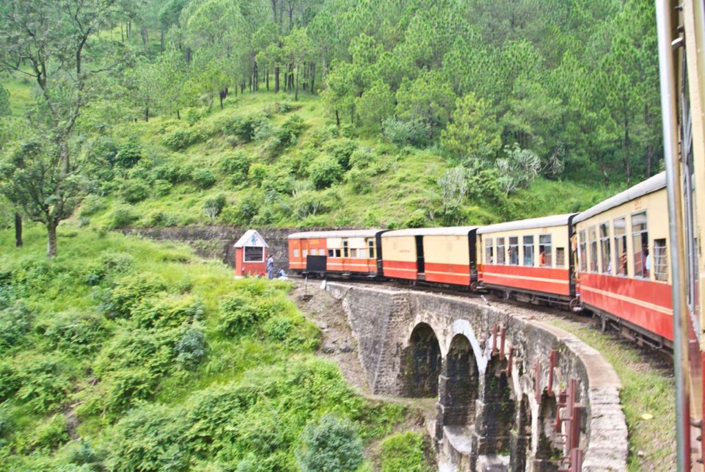 Darjeeling Toy Train passing through tea gardens with misty hills in the background — best places to visit in summer in India for heritage charm.