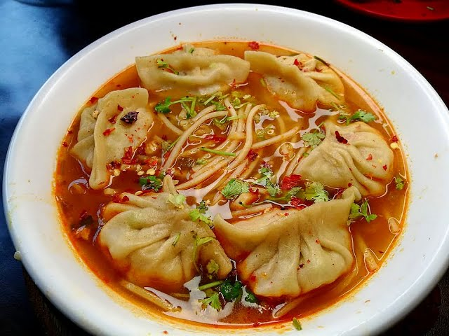 Steaming bowl of thukpa and plate of momos in a cozy Himalayan café — best places to visit in summer in India for food and culture.