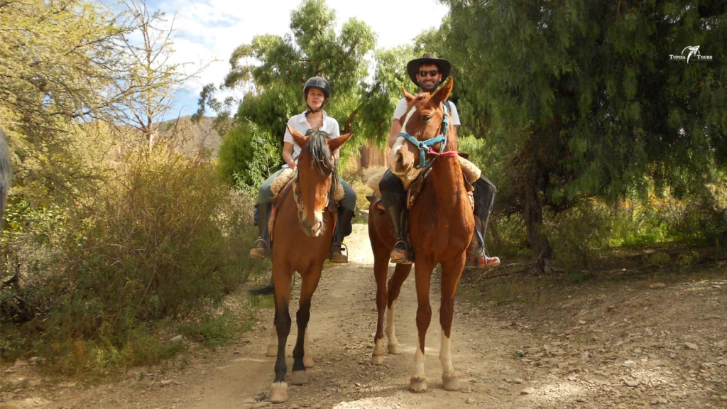 Traveler on horseback riding through red canyons in Tupiza — one of the most scenic things to do in Bolivia.